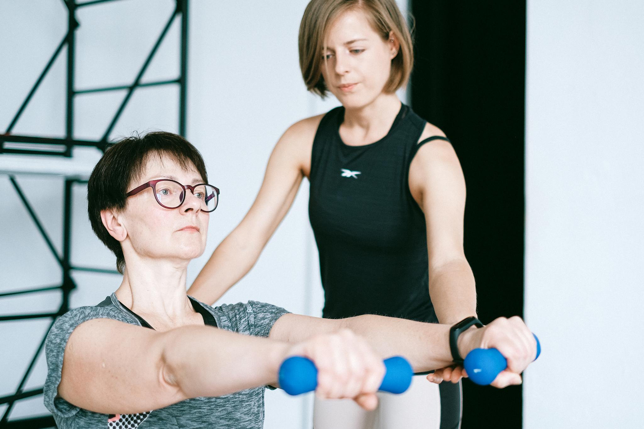 A Personal Trainer Guides A Woman Lifting
